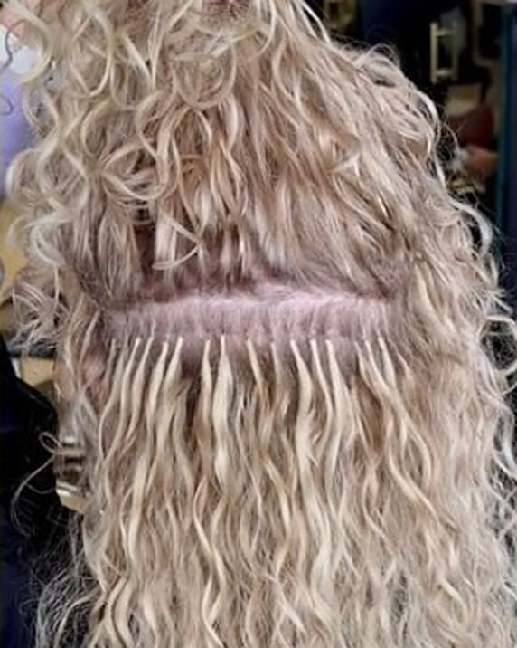 Blonde curly extensions placed in a neat row of tips