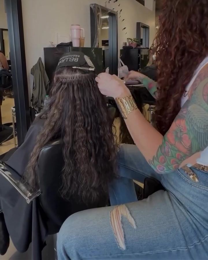 Extensions being installed into long curly hair at Republic Hair Co